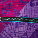 Black leather dog collar with turquoise stones on a purple beach towel
