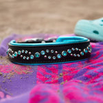 Decorative dog collar with rhinestones on a colorful towel with sandals in the background.