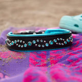 Decorative dog collar with rhinestones on a colorful towel with sandals in the background.