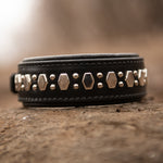 Black leather dog collar with metallic studs on a rock surface