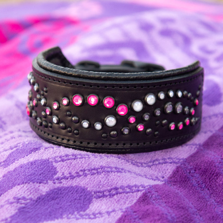 Black leather collar with pink and silver studs on a purple beach towel
