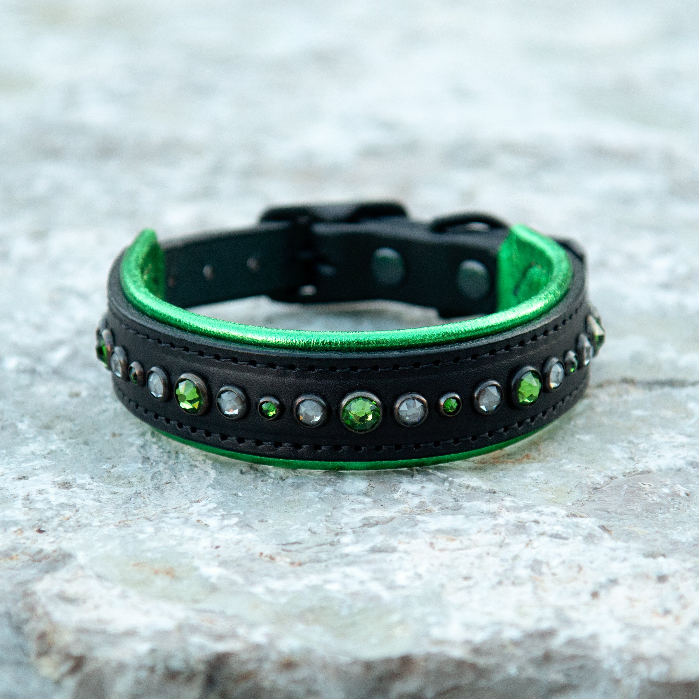 Black and green leather dog collar  on a textured surface