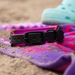 Buckle view of black dog collar on a colorful beach towel.