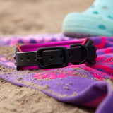 Buckle view of black dog collar on a colorful beach towel.